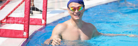 Man in swimming goggles and cap playing water polo