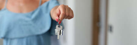 Woman with red manicure holding apartment keys in her hands closeup