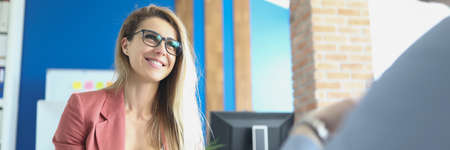 Business woman with glasses sitting at table and conducting interview with manの写真素材