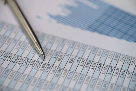 Metal pen lying on documents with graphs closeupの写真素材