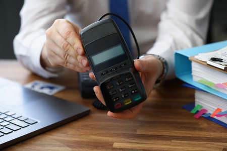Man holding modern credit card reader machine for cashless paymentの写真素材
