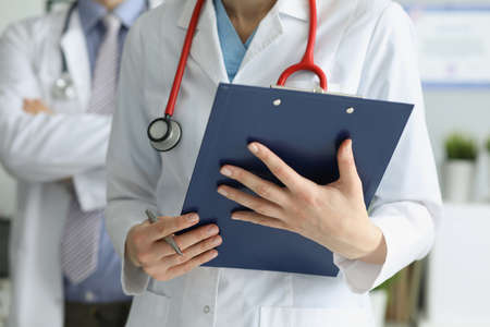 Medical coworkers in uniform posing in clinic with prescription paperの写真素材