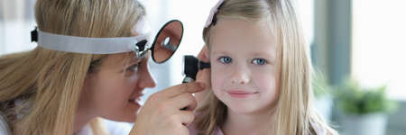 ENT doctor looks at little girls ears with otoscope closeupの写真素材