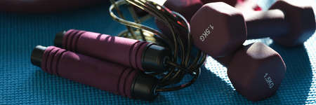 Sports accessories dumbbell skipping rope lie on mat closeup