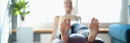 Woman performs sports exercises on ball at home closeupの写真素材