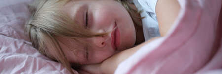 Little girl sleeping in pink bed at homeの写真素材