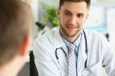 Young male doctor listens to a patient, close-up faceの写真素材