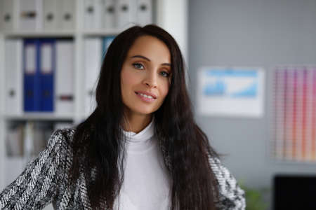 Attractive young businesswoman wearing stylish jacket posing in company office