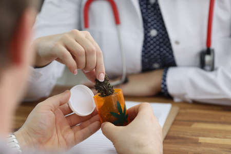 Doctor give bottle with dried cannabis to patient for health treatmentの写真素材