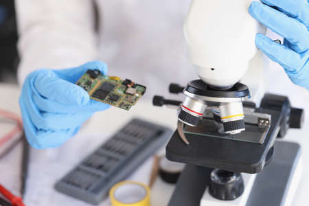 Person put smartphone component under microscope for investigationの写真素材