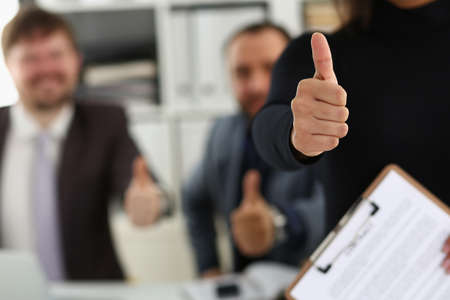 Group of young businesspeople happy to make good deal show thumbs up