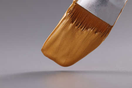 Closeup of brush with gold paint on gray backgroundの写真素材