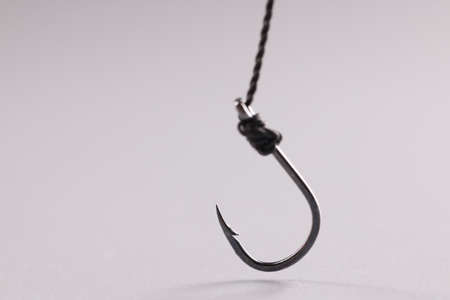 Closeup of fishing hook on string on gray backgroundの写真素材