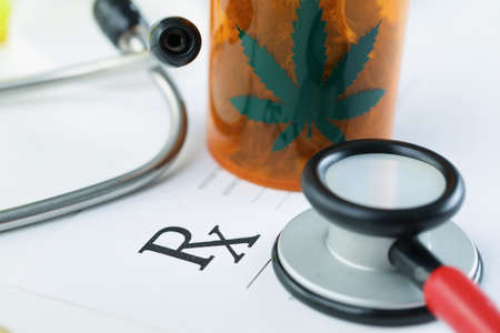 Plastic bottle with dried marijuana on blank medical prescription paperの写真素材
