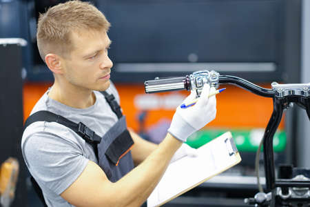 Young locksmith conducts diagnostics of motorcycle in service center