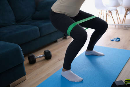 Woman doing exercises with elastic tape on her legs