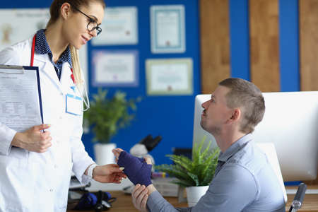 Female doctor support male patient with broken wrist in bandage