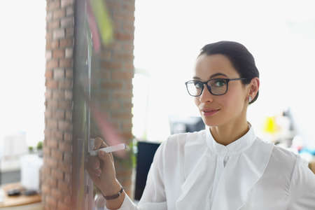 Businesswoman make notes on board with goals for next year, preparing report of done workの写真素材