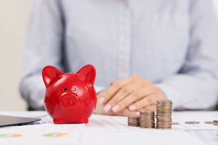 Person accountant on working place, stack of coins, red piggy bankの写真素材
