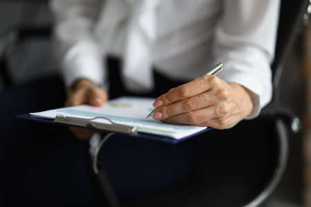 Female hand holding pen and put signature on business paper
