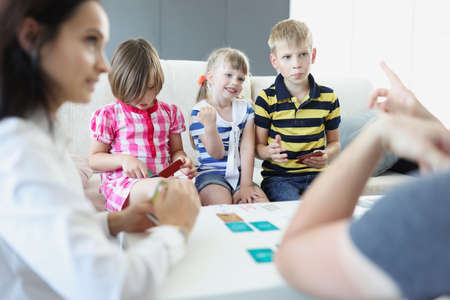 Cheerful children playing card game with parents at homeの写真素材