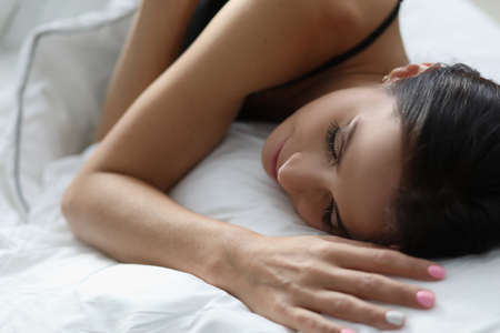 Young woman sleeping in white comfortable bedの写真素材