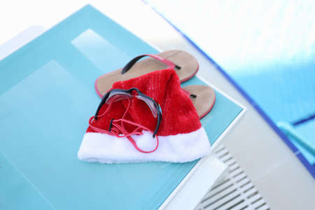 Hat of Santa Claus, swimming slippers on sunbedの写真素材