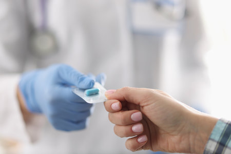 Female doctor in uniform give tablets in blister to patientの写真素材