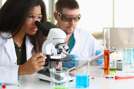 Two chemistry students conduct microscopic examinations in laboratory