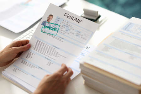 Hands holding resume of man for employment with stamp approved closeupの写真素材