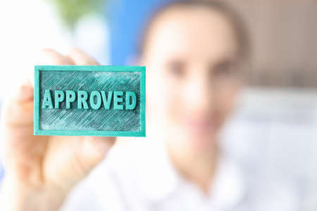 Woman holding green ink stamp approved closeupの写真素材