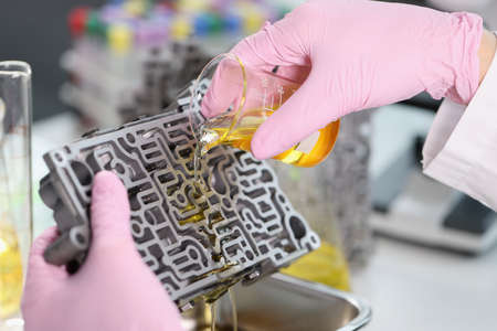 Mechanic man pouring liquid purified oil on automobile part