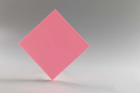 Pink sticker standing on sharp edge on grey backgroundの写真素材