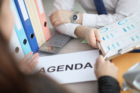 Man and woman sitting at table with documents with agenda closeupの写真素材