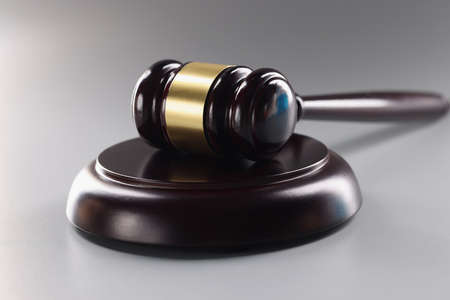 Close-up of judge black wooden hammer on soundboard on grey background, attorney instrument for...