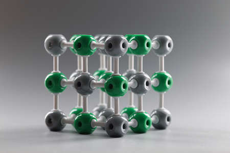 Close-up of molecular dna model structure on grey background, grey and green cells connected to each...