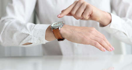 Businesswoman points to wristwatch on hand closeup