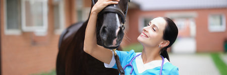 Smiling female veterinarian stroking black horse closeupの写真素材