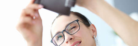 Portrait of young woman with glasses looks into empty purse. Constant shortage of money conceptの写真素材