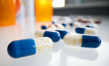 Medicine capsules and bottles of treat on white background closeup