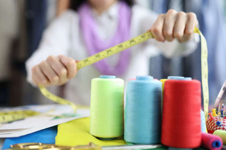 On the table of a seamstress are colored bobbins with threadsの写真素材