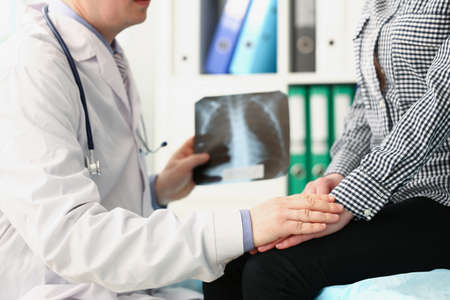 Qualified male doctor hold x ray scan of patients lungs and talk to clientの写真素材