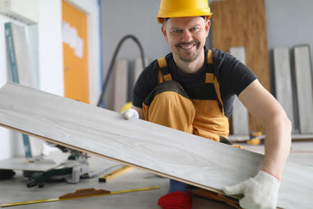 Qualified carpenter man carry wooden plank on working project, energetic workerの写真素材
