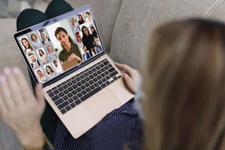 Young woman wave hi to coworkers connected online via video call, remote conferenceの写真素材