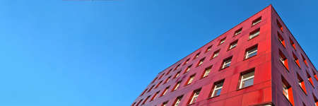 Multi-storey red building standing against blue sky backgroundの写真素材