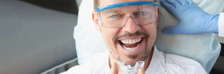 Dentist doctor inserting plastic night guard to man in dental office