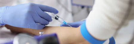 Nurse giving intravenous injection into patient ulnar vein at clinic closeupの写真素材