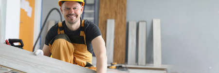 A man changes the floor covering, laminate in his hands.