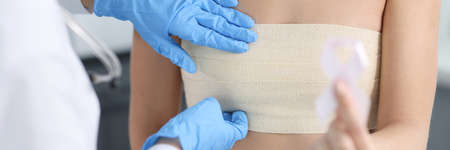 Doctor mammologist examining breast of female patient with elastic bandage closeupの写真素材