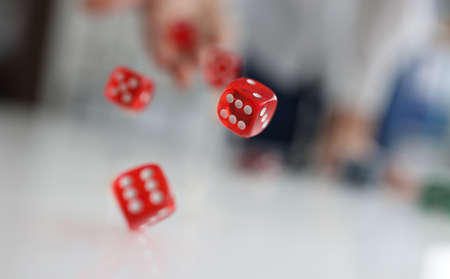 Woman hand throws red dice into air closeup